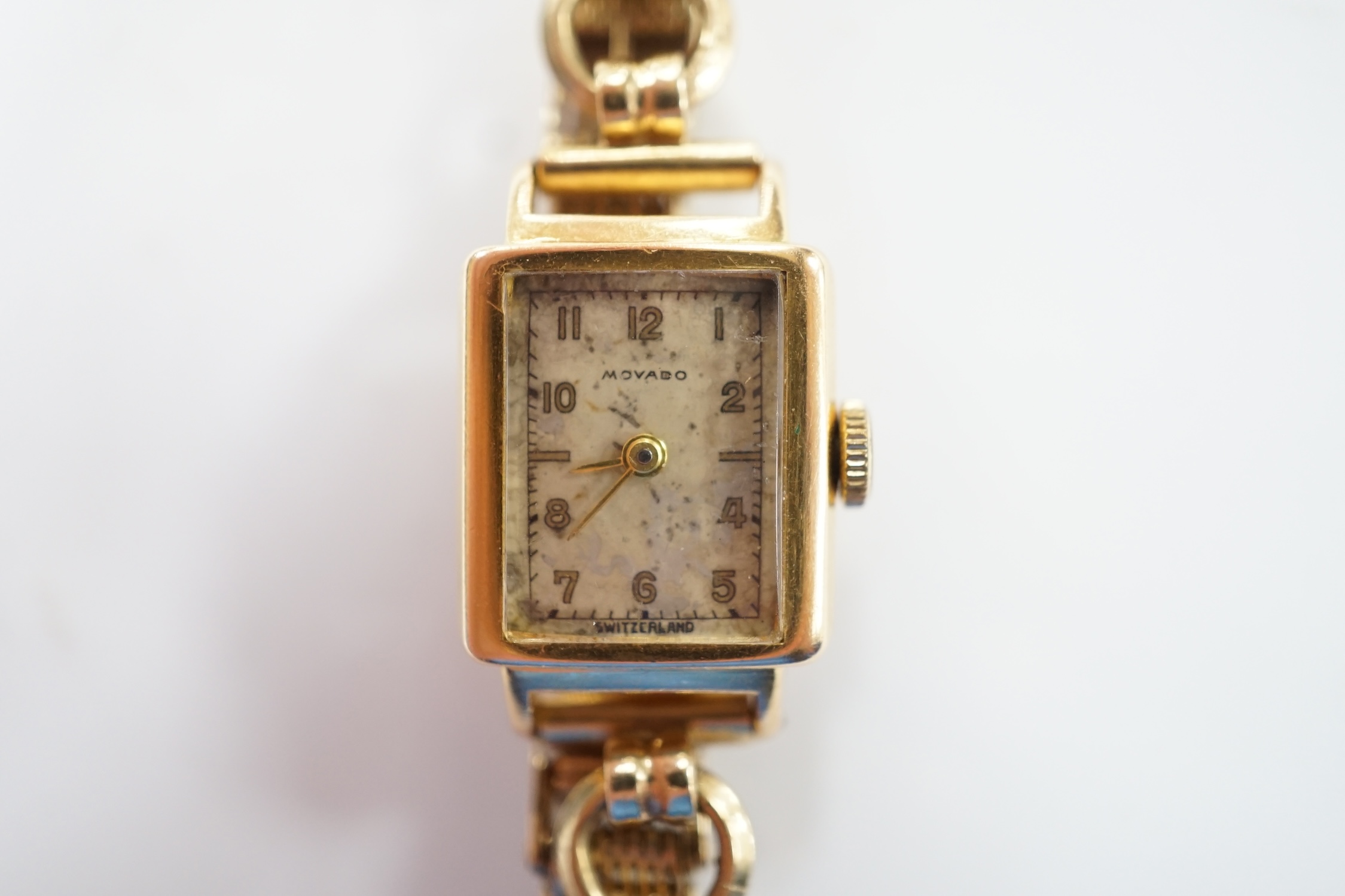 A lady's 18ct gold Movado manual wind wrist watch, on a 9ct gold bracelet. Fair condition